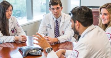 A photo of 4 residents meeting in a conference room.